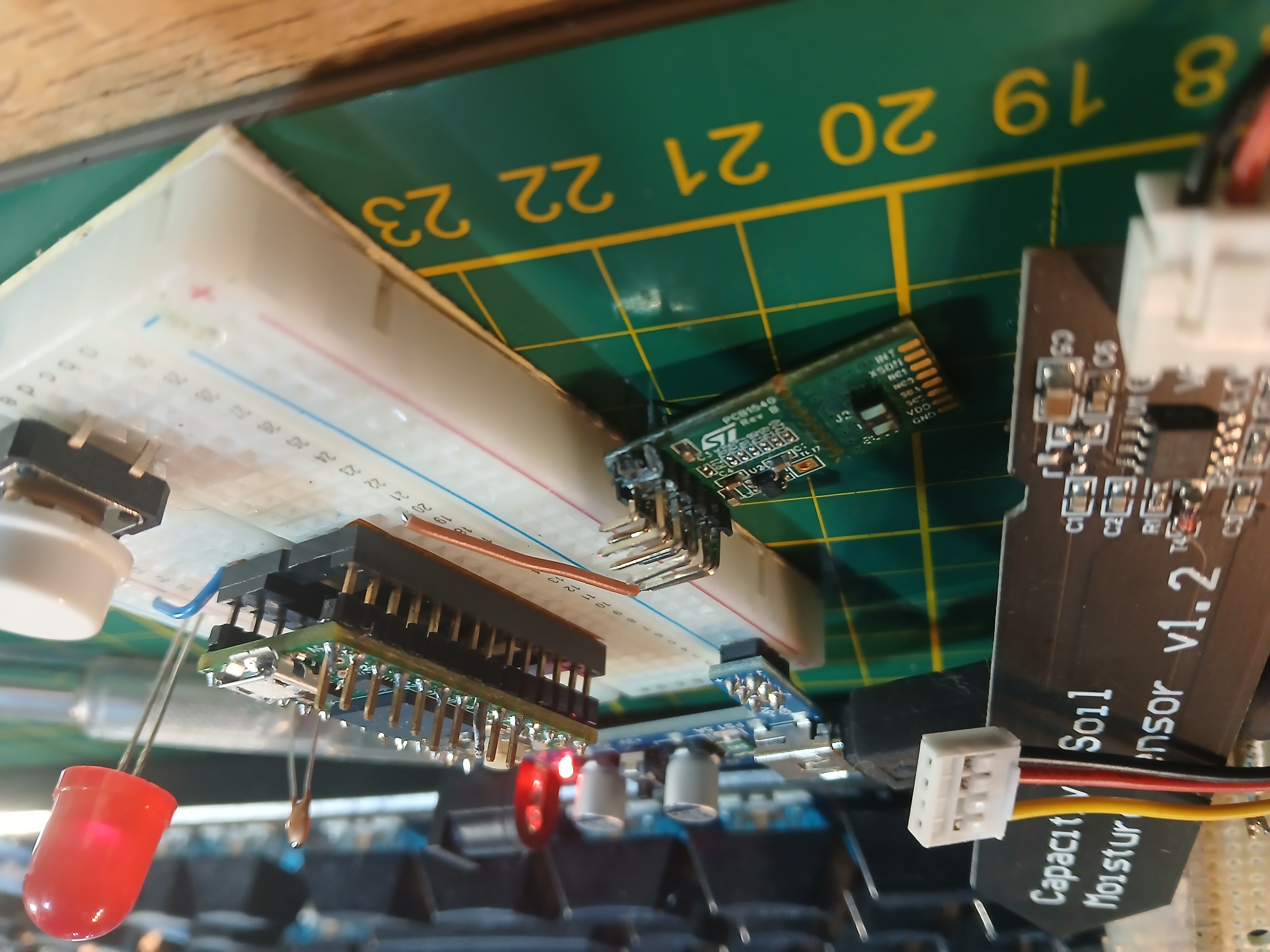 Workshop table covered in sensors and breadboards while a projection-mapped consent workflow glows overhead