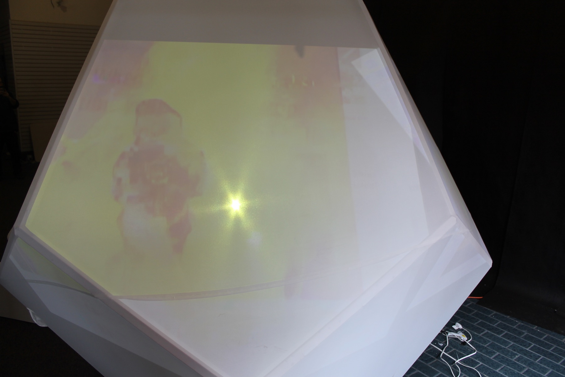Close view of a pale yellow and pink image projected across the translucent faceted surface.