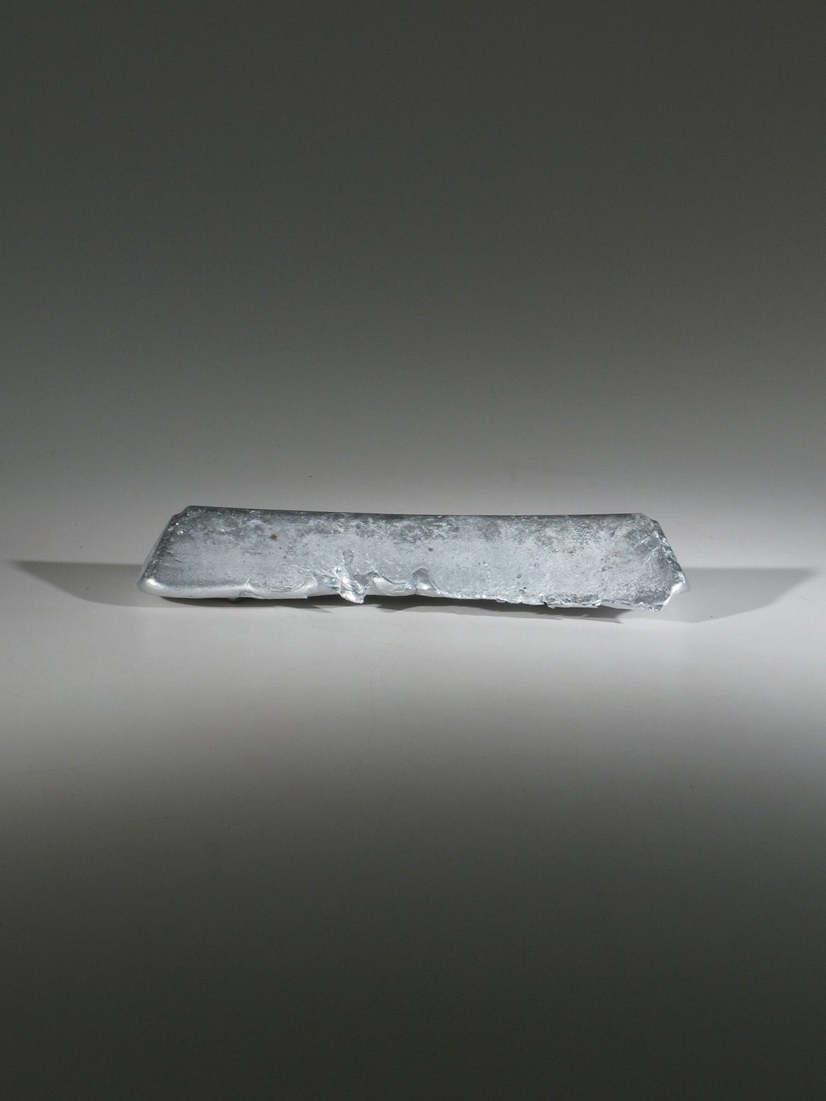 Small, low rectangular aluminum form with a rough and irregular cast surface.
