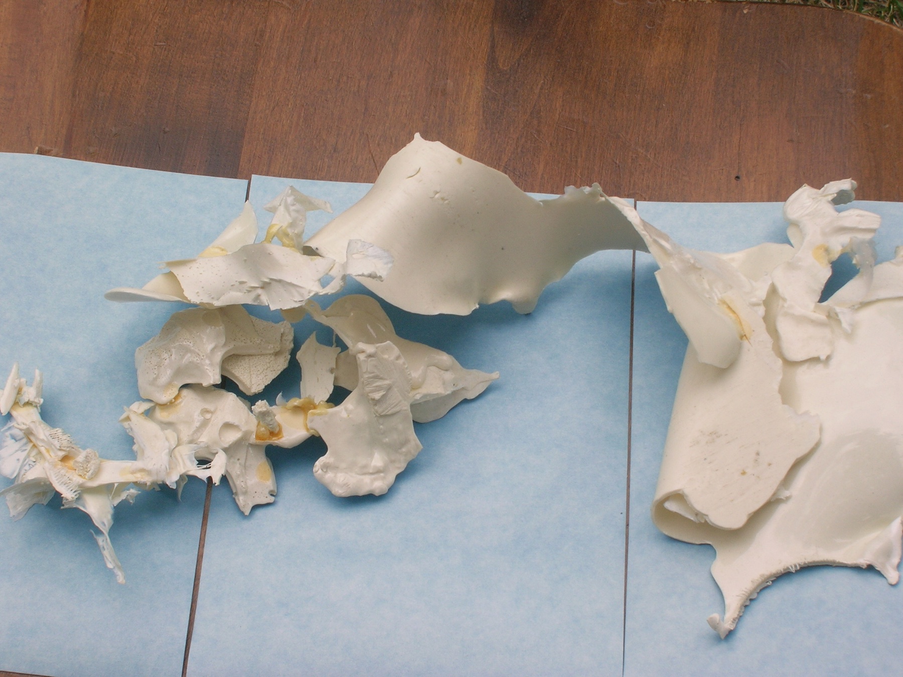 Close view of folded and clustered white cast-plastic forms arranged on blue paper.