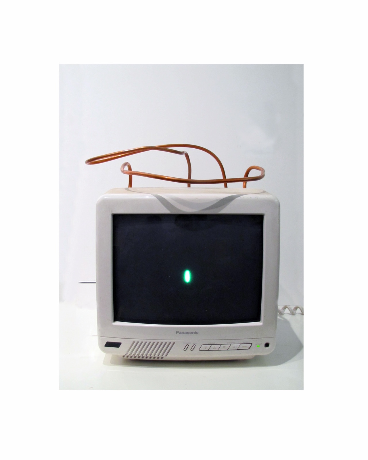 A small white Panasonic television with a single green point of light on its screen and a looping copper tube above it.